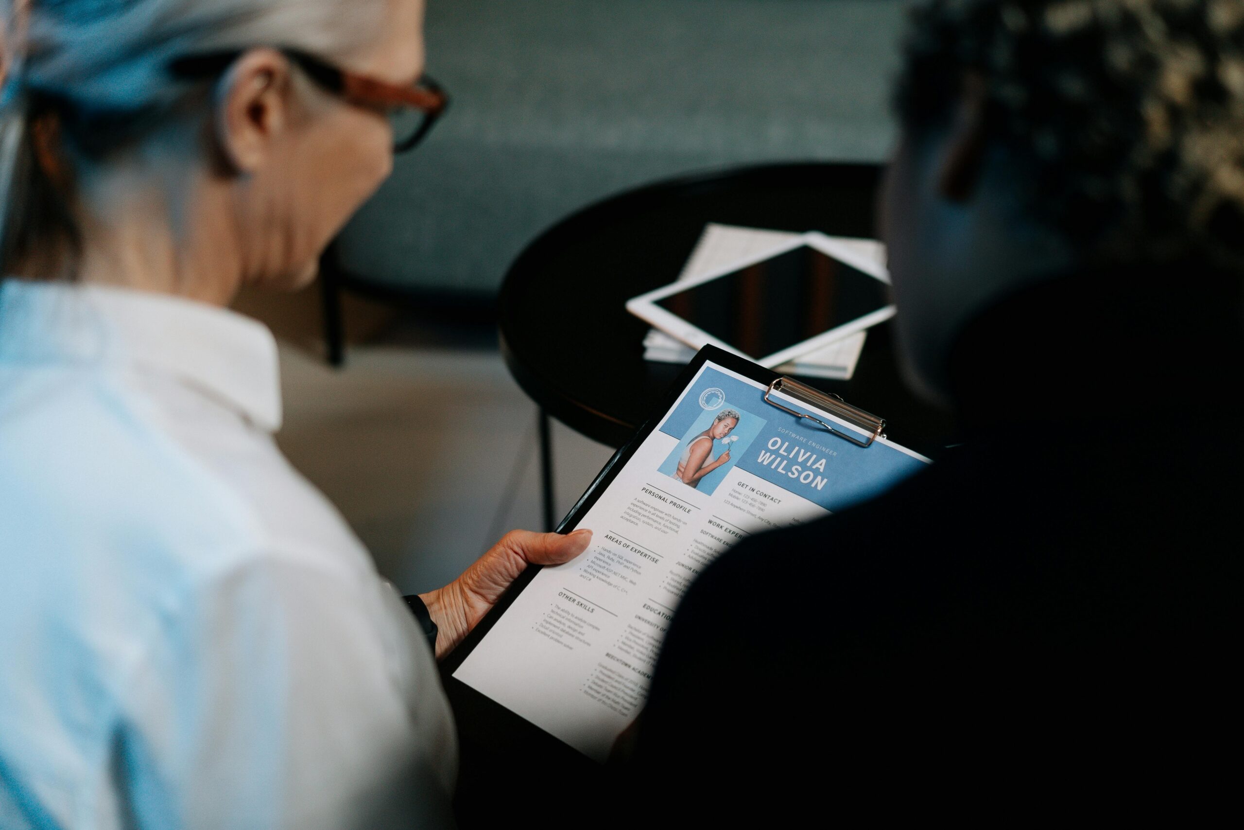 Services Business professionals conducting an interview with resume on clipboard in an office setting.